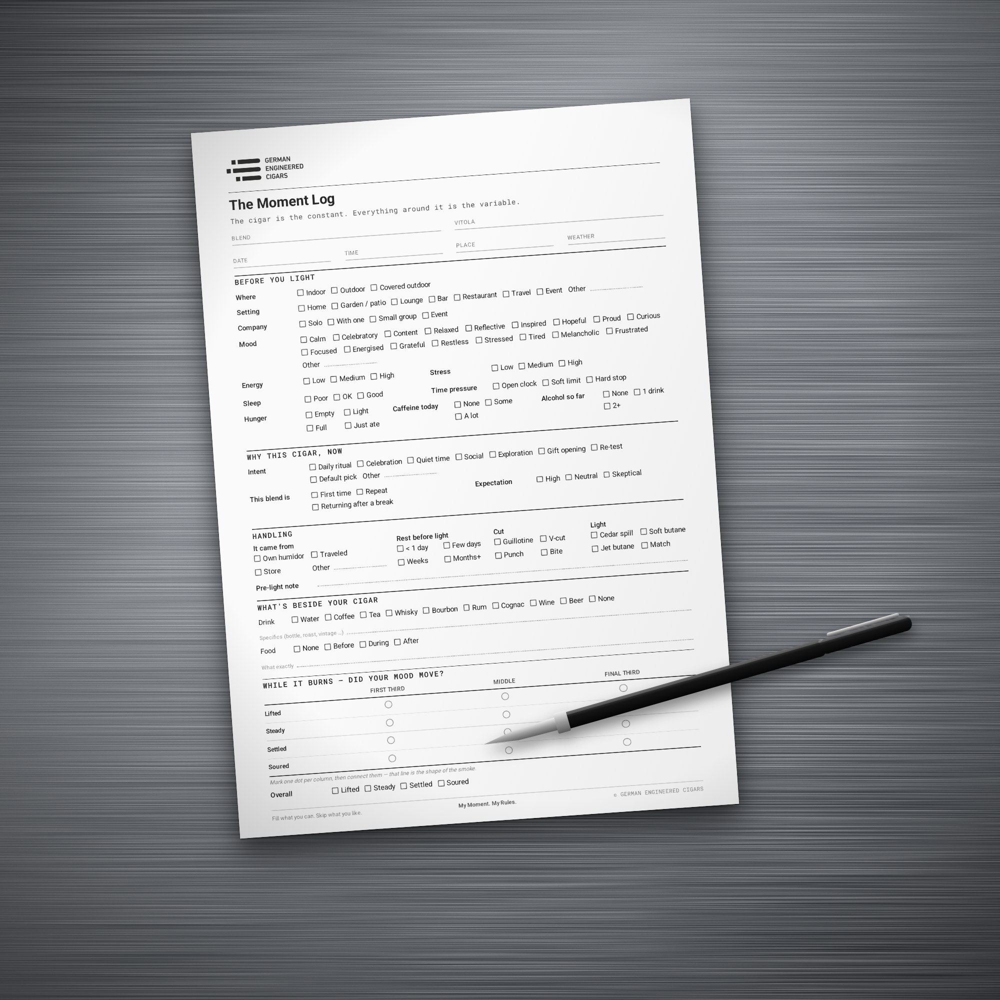 The printed Moment Log form on a brushed steel table with a black pen next to it